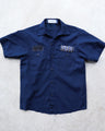 Navy one-of-one reworked mechanic shirt laid flat, with black chest patches, silver studs, and ATH label.